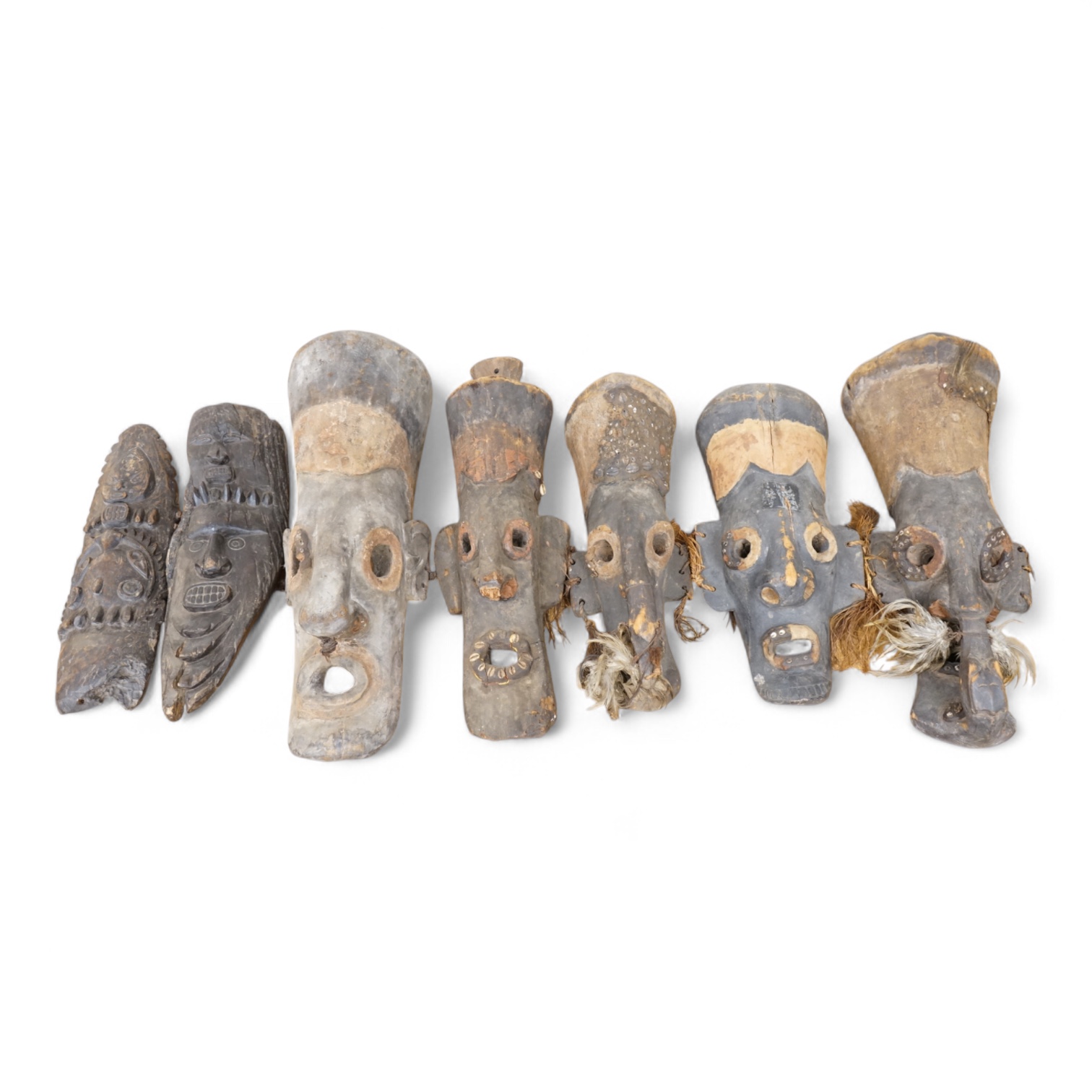 Papua New Guinea Septik River, a collection of five similar carved wooden masks of elongated form, applied in places with shells and two smaller masks with double face carving. Largest 80cm high.